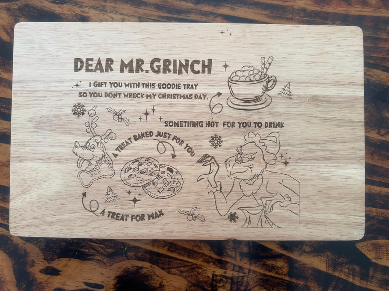 Wooden tray with engraved Christmas-themed design and text on a wooden surface.