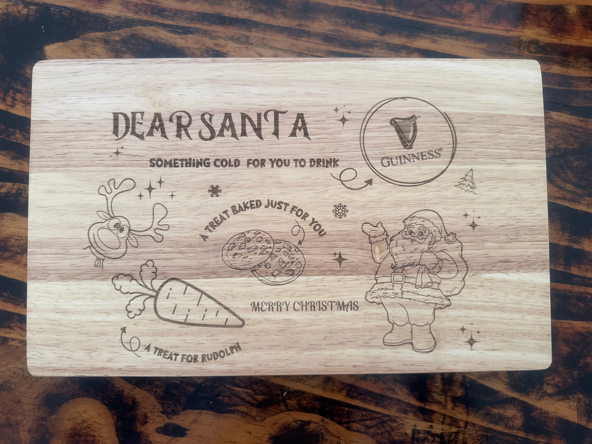 Wooden cutting board with engraved Christmas-themed design and Guinness logo on a wooden surface.