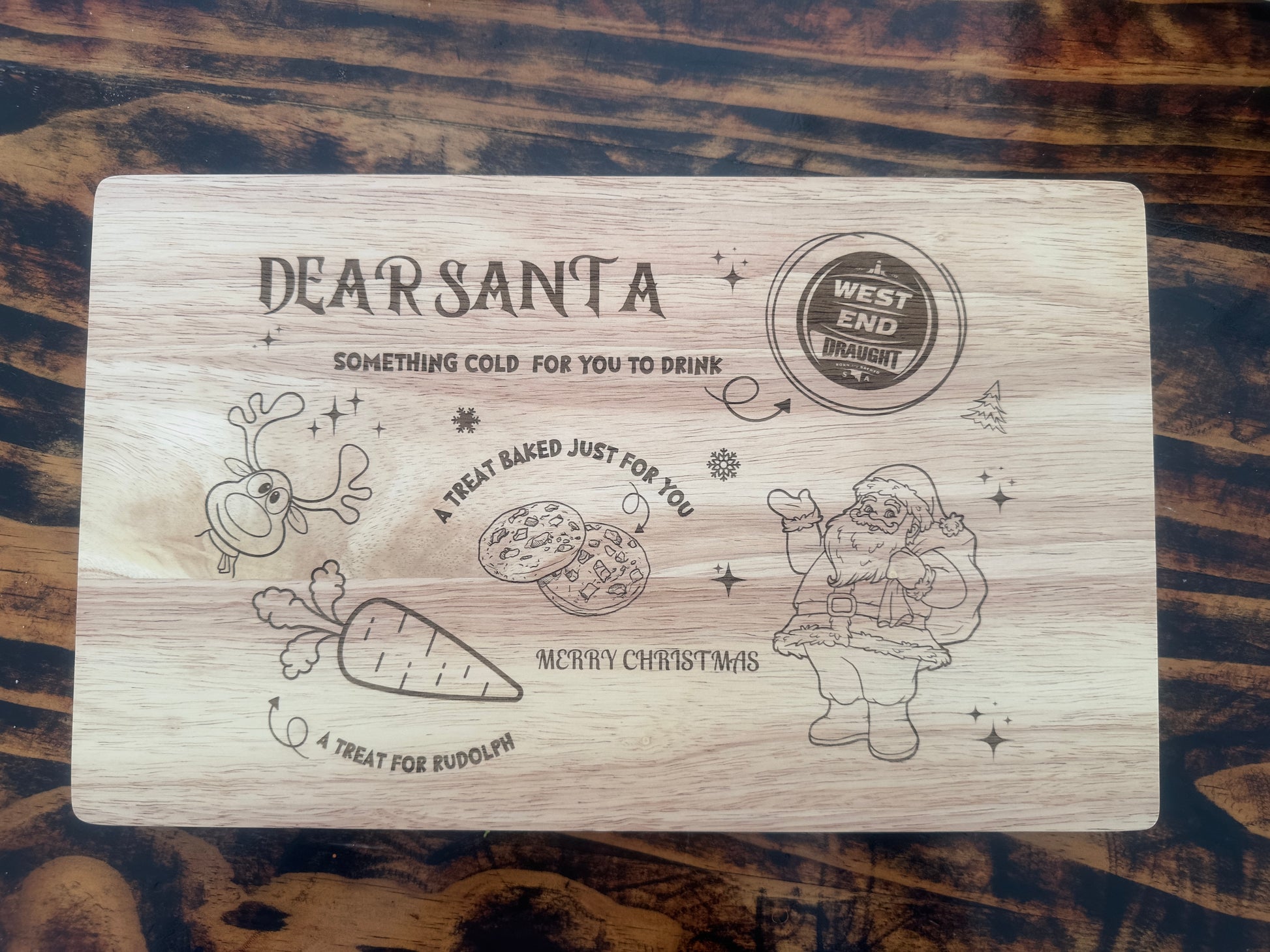 Wooden cutting board with engraved Christmas-themed design on a wooden surface