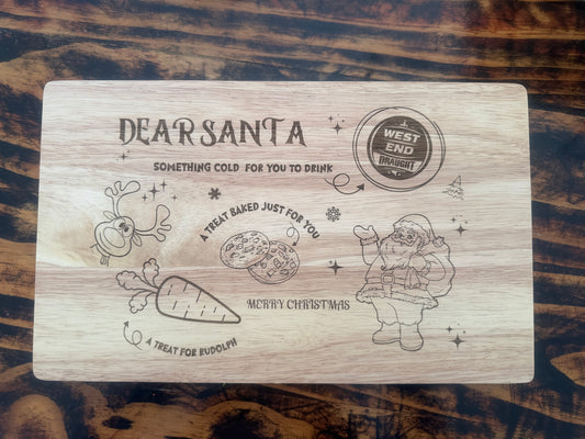 Wooden cutting board with engraved Christmas-themed design on a wooden surface